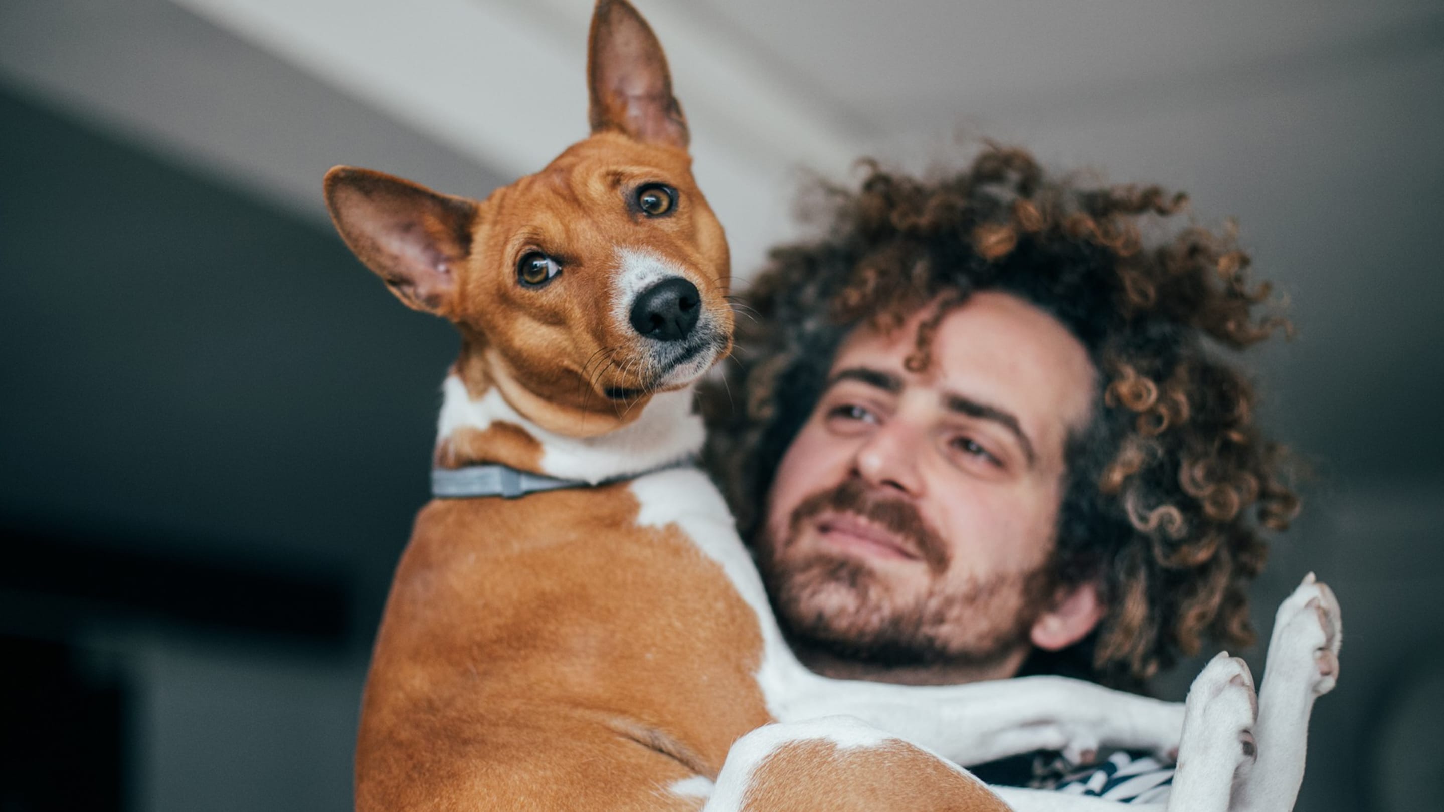 Tutor com seu cão no colo, os dois olhando para a câmera